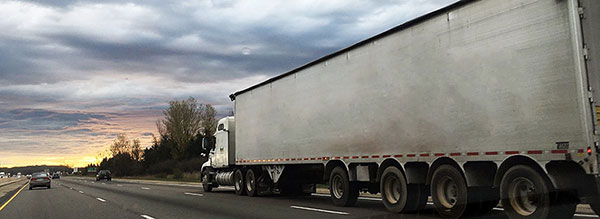 White freight truck on highway during cloudy sunset